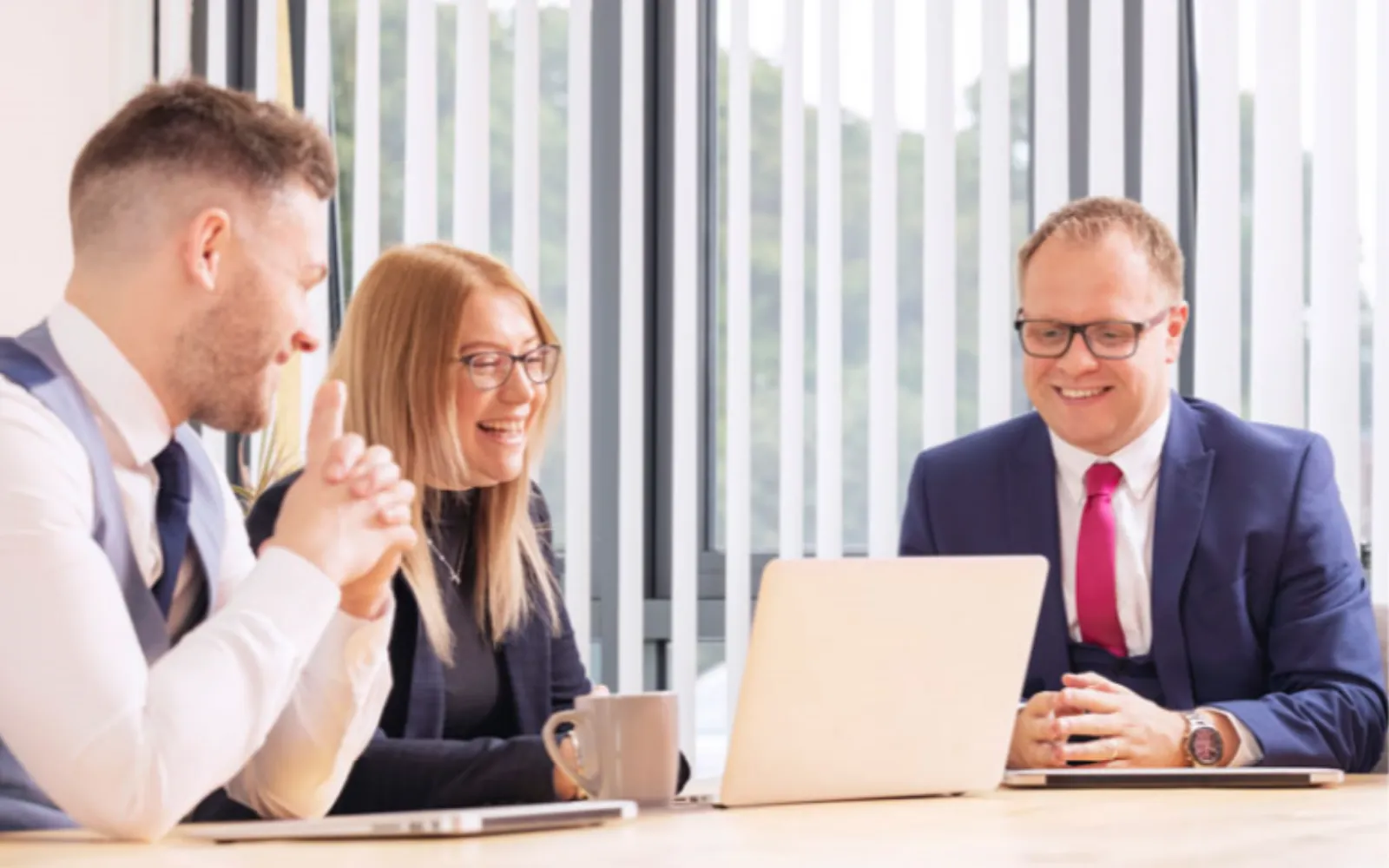 The photograph from the Hudson Procure homepage, from the Internet Archive's copy of November 2022: three colleagues smiling over a laptop at a meeting table
